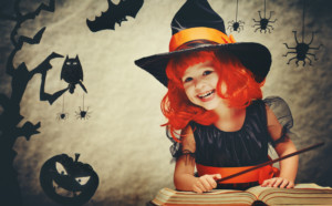 Halloween. cheerful little witch with a magic wand and the book conjure and laughs.