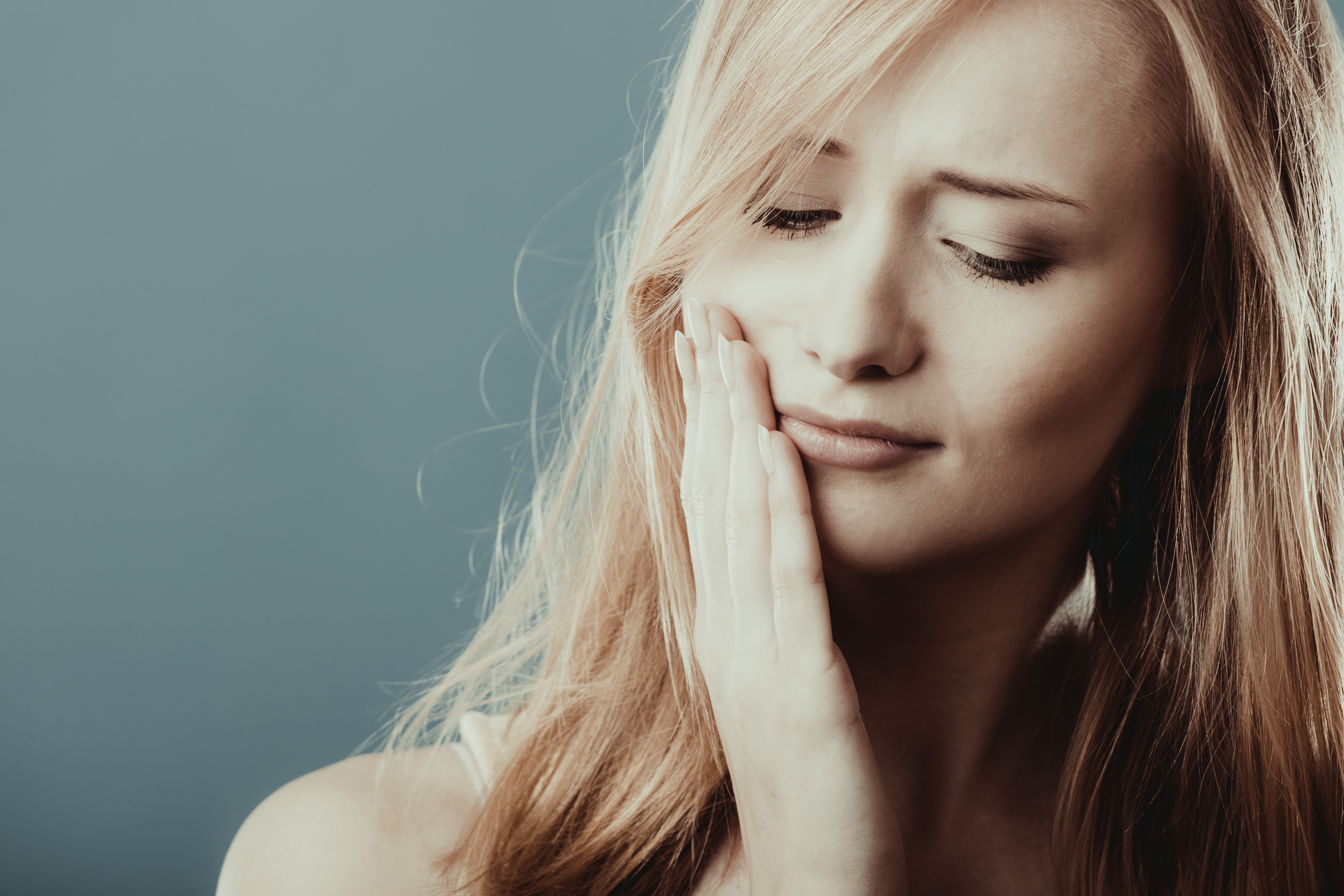woman suffering from jaw pain caused by TMJ