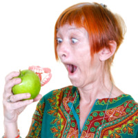 Woman losing her false teeth by biting into an apple