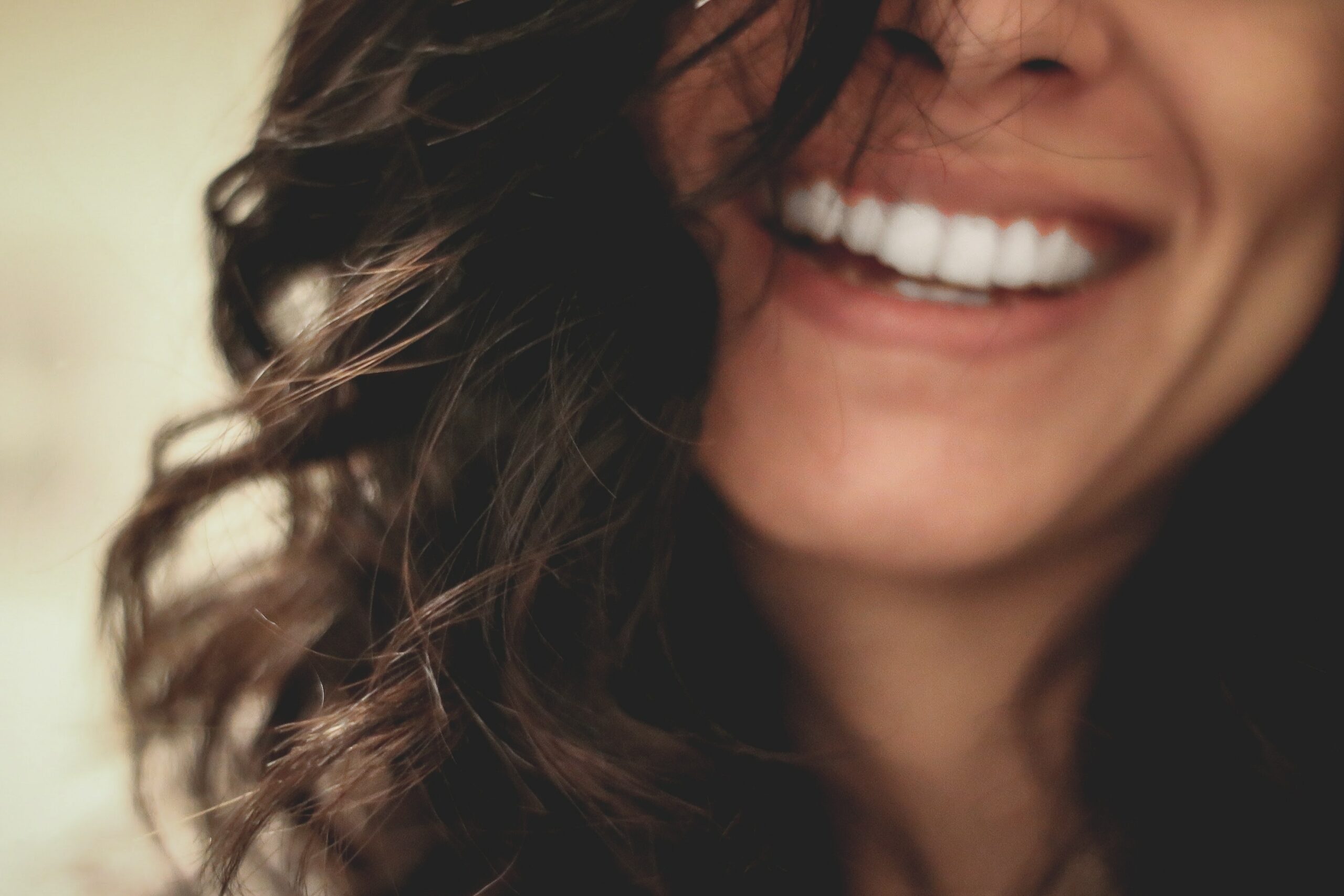 Curly-haired woman showcasing her brilliantly white, perfect smile