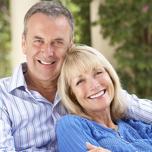 An older couple relaxing outside smile to show the power restorative dentistry can have on your smile.